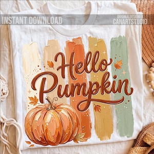 Puede incluir: Camiseta blanca con un dise&ntilde;o de oto&ntilde;o. La camiseta muestra las palabras "Hello Pumpkin" en marr&oacute;n, acompa&ntilde;adas de una ilustraci&oacute;n de calabaza y pinceladas coloridas en tonos naranja, beige y verde. Tambi&eacute;n se ve el texto "Instant Download".