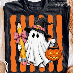 May include: A black t-shirt featuring a graphic of a white ghost wearing a black witch hat with a pink band. The ghost holds a yellow pencil with a pink bow and a jack-o'-lantern bucket. The background has vertical orange stripes.
