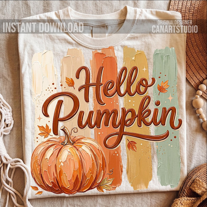 Puede incluir: Camiseta color crema con las palabras "Hello Pumpkin" en escritura marr&oacute;n, con una ilustraci&oacute;n de calabaza naranja. Detr&aacute;s del texto hay pinceladas verticales en tonos beige, naranja, amarillo y verde. Tambi&eacute;n se ven las palabras "Instant Download" y "Original Designer CanArtStudio".