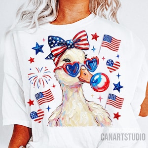Op de afbeelding: Wit T-shirt met een grillige eend met een hartvormige zonnebril en een patriottische strik. De eend blaast een bel, omringd door Amerikaanse vlaggen en sterren. De tekst "CANARTSTUDIO" staat onderaan.