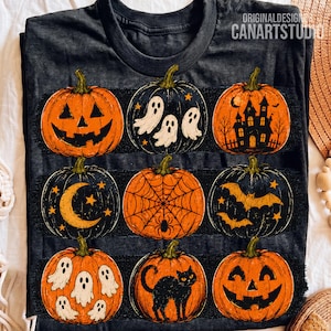 May include: A dark gray t-shirt featuring a grid of nine pumpkins with various Halloween illustrations, including jack-o'-lantern faces, ghosts, a haunted house, a crescent moon, a spider web, bats, and a black cat. Text reads ORIGINALDESIGN CANARTSTUDIO.