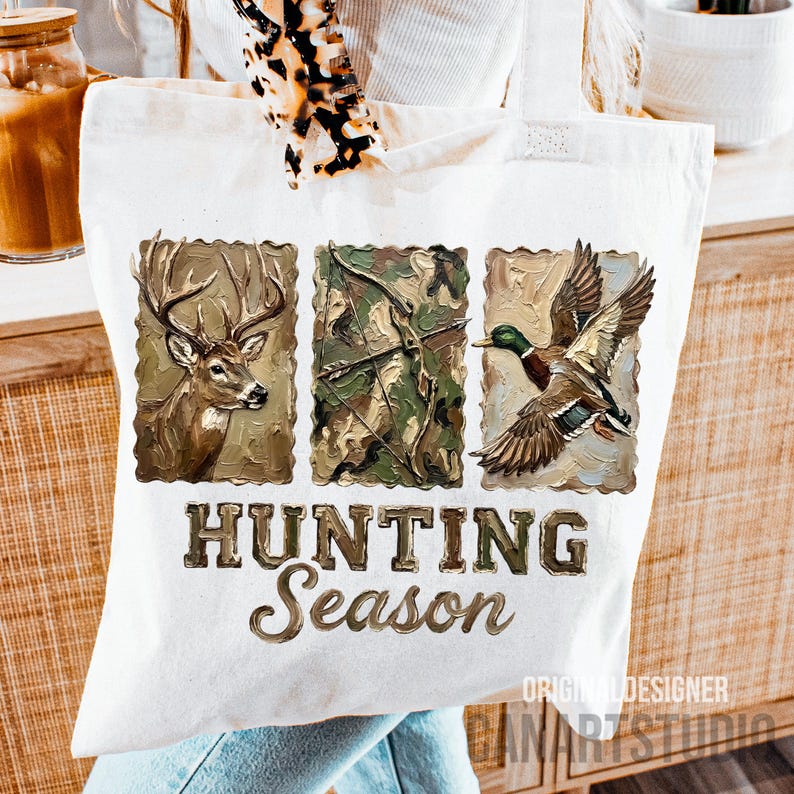 May include: A white tote bag featuring three rectangular images: a deer, a bow and arrow, and a duck in flight. The words "HUNTING Season" are printed in a brown, textured font below the images. The bag has a hunting theme.