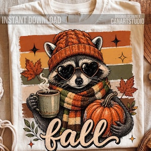 Puede incluir: Una camiseta color crema con el gr&aacute;fico de un mapache que lleva un gorro de punto naranja, gafas de sol en forma de coraz&oacute;n y una bufanda a rayas. El mapache sostiene una taza humeante y una calabaza. Incluye el texto "INSTANT DOWNLOAD" y "fall".