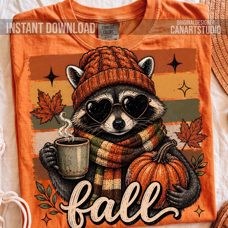Puede incluir: Una camiseta naranja con el gr&aacute;fico de un mapache que lleva un gorro de punto y una bufanda a rayas, sosteniendo una taza humeante y una calabaza. El mapache lleva gafas de sol en forma de coraz&oacute;n. El dise&ntilde;o incluye hojas y la palabra fall.