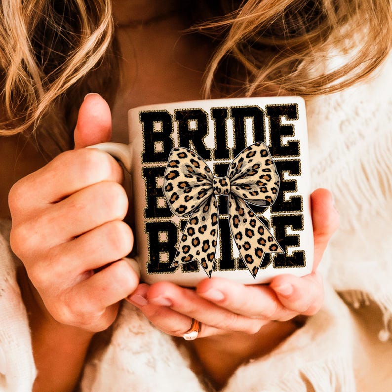 May include: White ceramic mug with the word "BRIDE" repeated three times in black text. A large leopard print bow is centred between the words.
