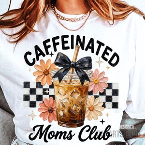 May include: White t-shirt featuring a graphic of an iced coffee with a black bow, surrounded by flowers and a checkered pattern. The text reads "CAFFEINATED Moms Club."