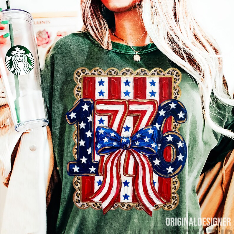 May include: Green long-sleeve shirt with a patriotic design. The design features the number "1776" in blue and white, with a red and white striped background and a blue bow. The shirt has a leopard print border.