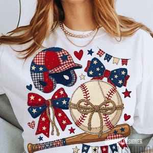 Puede incluir: Camiseta blanca con gráficos patrióticos de béisbol. El diseño incluye un casco, una pelota de béisbol, lazos y un bate de béisbol, todos adornados con estrellas y rayas rojas, blancas y azules. La camiseta tiene cuello redondo.