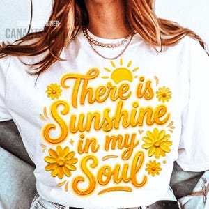 Peut inclure: T-shirt blanc avec l'inscription "There is Sunshine in my Soul" en jaune, entour&eacute;e de fleurs jaunes et d'un soleil. Un v&ecirc;tement d&eacute;contract&eacute; pour un usage quotidien.