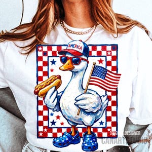 May include: White t-shirt featuring a patriotic goose wearing sunglasses, a baseball cap with "AMERICA" on it, and blue star-patterned shoes. The goose holds a hot dog and an American flag. The design is framed by a red and white checkered border.