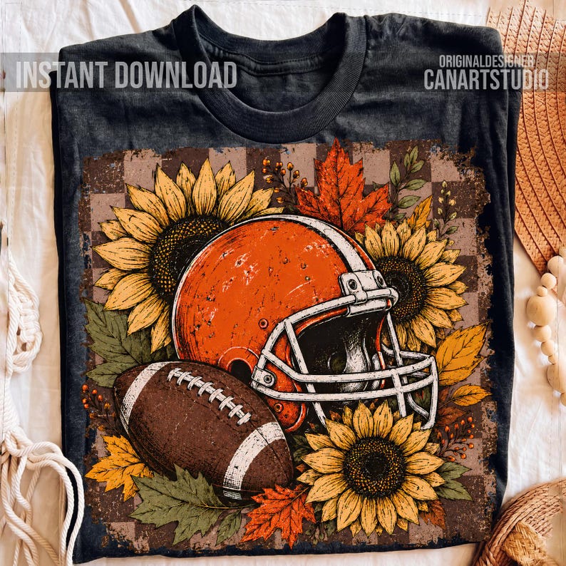 May include: A dark gray t-shirt featuring a graphic of an orange football helmet, a brown football, sunflowers, and autumn leaves. The text "INSTANT DOWNLOAD" and "ORIGINAL DESIGNER CANARTSTUDIO" is printed on the shirt in white lettering.