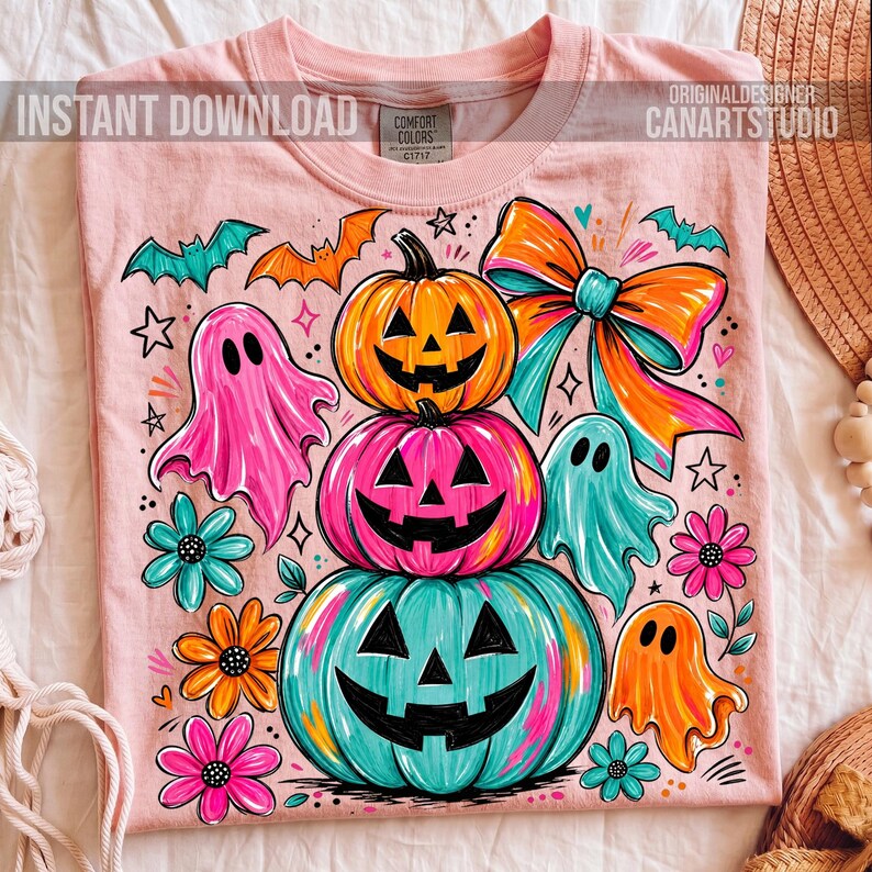 Op de afbeelding: Roze T-shirt met een kleurrijk Halloween-ontwerp. Het ontwerp toont gestapelde pompoenen, geesten, vleermuizen, bloemen en een grote strik. De tekst "INSTANT DOWNLOAD" en "ORIGINAL DESIGNER CANARTSTUDIO" staat op het shirt.