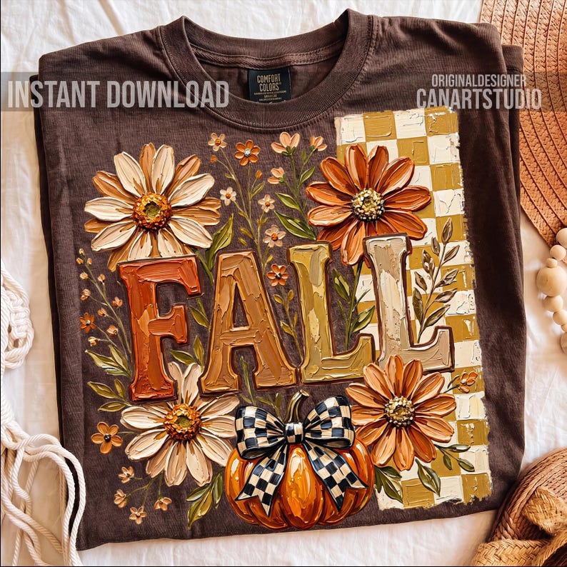 May include: Brown t-shirt with a fall-themed design. The design includes the word "FALL" in large, textured letters, surrounded by flowers, a pumpkin with a checkered bow, and a checkered background. The shirt also has the text "INSTANT DOWNLOAD" and "CANARTSTUDIO".