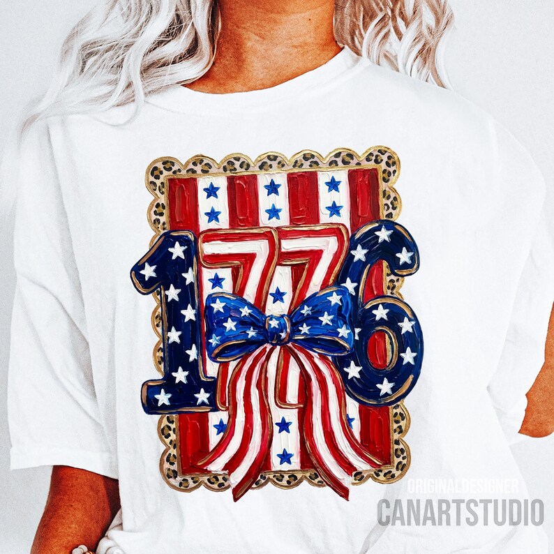 May include: White t-shirt featuring a patriotic design with the number "1776" in blue and red, adorned with stars and stripes. A blue bow with white stars is centered below the numbers. The design is framed with a leopard print border.