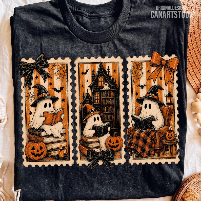 Op de afbeelding: Een donkergrijs t-shirt met drie rechthoekige, postzegelachtige illustraties van geesten met heksenhoeden die boeken lezen. De ontwerpen bevatten pompoenen, een spookhuis, spinnenwebben, vleermuizen en decoratieve strikken in oranje en zwart.