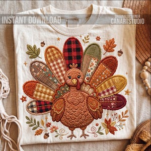 May include: Off-white t-shirt with an embroidered turkey design. The turkey has a patchwork tail in various patterns and colours, with autumn leaves, acorns, and floral details. The text "INSTANT DOWNLOAD" and "ORIGINAL DESIGNER CANARTSTUDIO" are printed on the shirt.
