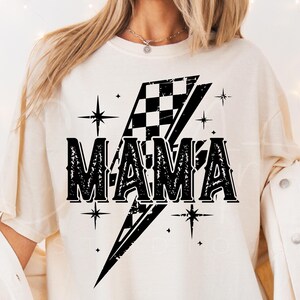 May include: White t-shirt with a black graphic of a checkered flag lightning bolt and the word "MAMA" in a vintage font.