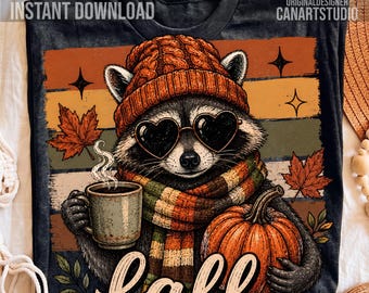 May include: A black t-shirt featuring a graphic of a raccoon wearing an orange knit beanie, heart-shaped sunglasses, and a striped scarf. The raccoon holds a steaming mug and a pumpkin. The background has autumn leaves and the text "fall".