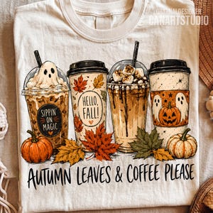 May include: A cream-colored t-shirt featuring a graphic of four coffee cups with autumn themes, including a ghost, pumpkins, and maple leaves. The text reads "Sippin' on Magic," "Hello, Fall!," and "Autumn Leaves & Coffee Please" in black lettering.