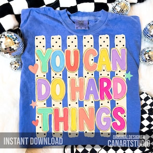 May include: A blue Comfort Colors sweatshirt with the text "YOU CAN DO HARD THINGS" in colorful bubble letters. The design includes vertical stripes, hearts, and stars. The words "INSTANT DOWNLOAD" and "CANARTSTUDIO" are also visible.
