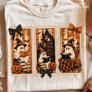 Op de afbeelding: Een cr&egrave;mekleurig t-shirt met drie rechthoekige panelen met geschulpte randen. De illustraties tonen geesten met heksenhoeden die boeken lezen, omringd door pompoenen, een spookhuis, spinnenwebben, vleermuizen en decoratieve strikken.