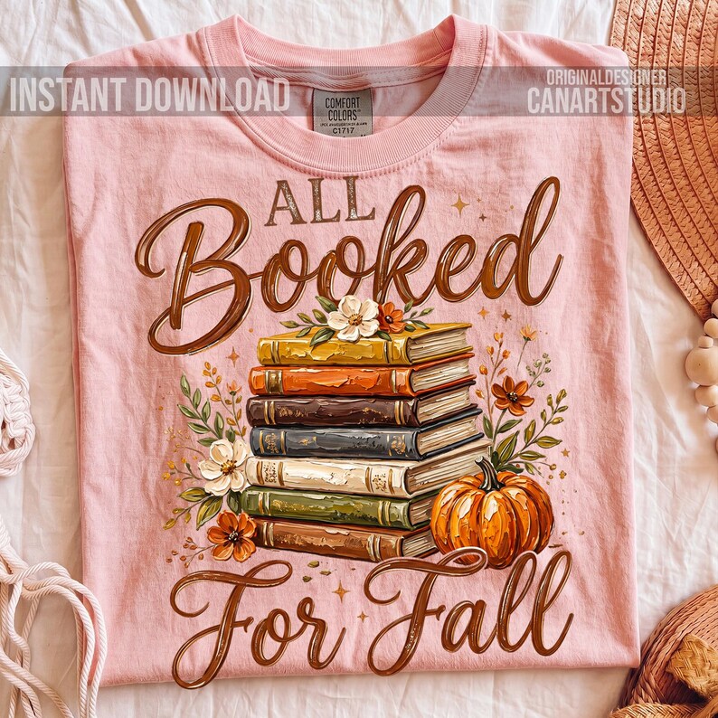 May include: A light pink t-shirt featuring a stack of books, flowers, and a pumpkin. The words "All Booked For Fall" are written in a brown script. The shirt also has the words "Instant Download" and "Original Designer Canartstudio".
