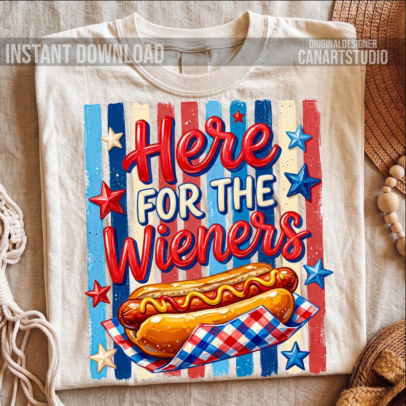 May include: Cream-colored t-shirt with a graphic design featuring a hot dog and the text "Here For The Wieners" in red and white. The design includes red, white, and blue stripes and stars, with the words "Instant Download" and "Original Designer CanArtStudio".