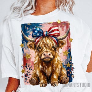 Peut inclure: T-shirt blanc avec une illustration de vache des Highlands. La vache porte un n&oelig;ud et un bandeau patriotiques aux couleurs du drapeau am&eacute;ricain. Des &eacute;toiles dor&eacute;es et un imprim&eacute; l&eacute;opard ornent le fond. Le texte "CANARTSTUDIO" est visible.
