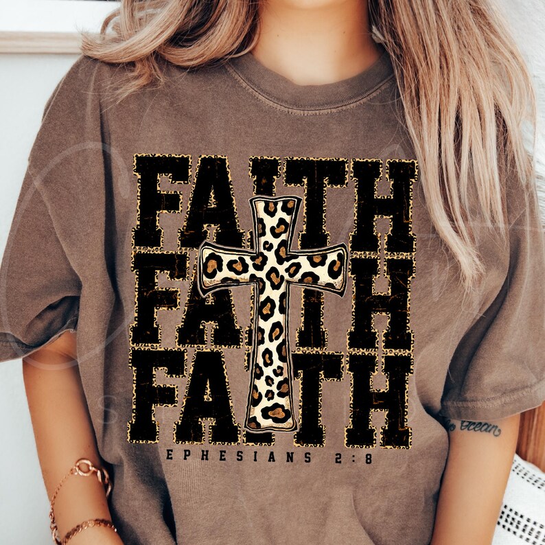 May include: A brown t-shirt with the word "FAITH" repeated three times in black with a leopard print cross in the center. The text "EPHESIANS 2:8" is printed below the word "FAITH".