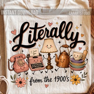 May include: A cream-colored t-shirt featuring a graphic print with the text "Literally from the 1900's". The design includes cartoon illustrations of a pink rotary phone, a pink typewriter with a note saying "I Love You", a lamp, a kettle, and a stack of cups.