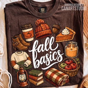 May include: A dark brown t-shirt featuring a graphic print with the text fall basics in white script. The design includes a coffee cup, orange knit hat, acorn, pumpkin pie slice, candle, sweater, lantern, stack of books, blanket, and apple basket.