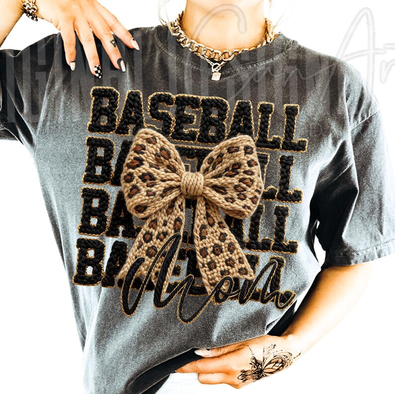 May include: Gray t-shirt with the words "BASEBALL MOM" in black and gold lettering. A large bow with a leopard print design is centered on the shirt. The shirt has short sleeves and a relaxed fit.