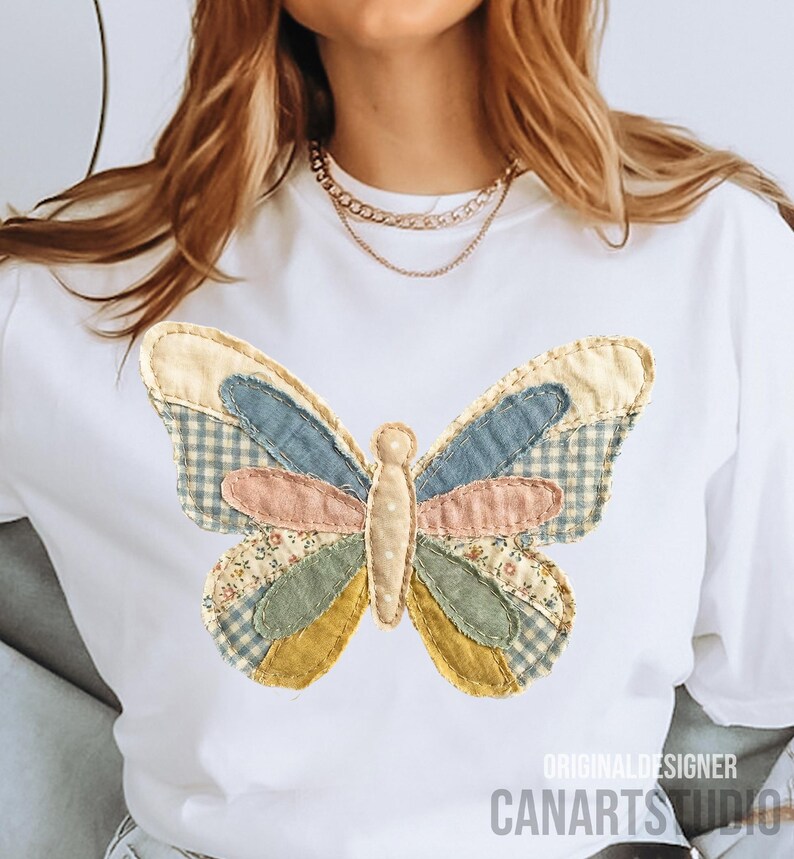 May include: White t-shirt featuring a colorful butterfly applique. The butterfly design incorporates various fabric patterns and colors, including blue gingham, floral, and solid pastel hues. The text "ORIGINAL DESIGNER CANARTS STUDIO" is printed at the bottom.