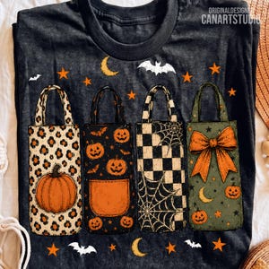 May include: A dark gray t-shirt featuring a graphic of four tote bags with Halloween themes. The bags display leopard print with a pumpkin, a black pattern with pumpkins, a black and white checkerboard with spiderwebs, and an olive green design with a large orange bow and pumpkins. The text "ORIGINALDESIGN CANARTSTUDIO" appears in the top right corner.