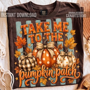 May include: A dark brown t-shirt featuring a graphic of three pumpkins with bows, surrounded by autumn leaves and vertical light blue stripes. The text reads "TAKE ME TO THE pumpkin patch" in orange and white lettering with a fall-themed design.