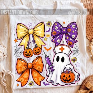 May include: A white t-shirt featuring a graphic print of three decorative bows, a ghost dressed as a nurse holding a syringe, and a jack-o'-lantern bucket. The design includes small stars, flowers, bats, and spiderwebs in yellow, orange, and purple.