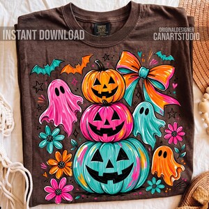 Op de afbeelding: Bruin t-shirt met een Halloween-thema. Het heeft gestapelde pompoenen met uitgesneden gezichten, geesten, vleermuizen en bloemen in levendige kleuren. Het shirt bevat de tekst "INSTANT DOWNLOAD" en "ORIGINALDESIGNER CANARTSTUDIO".