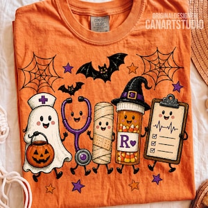 May include: An orange t-shirt featuring a Halloween-themed graphic of a ghost nurse holding a jack-o'-lantern, a stethoscope, a mummy, a prescription bottle with a witch hat, and a clipboard with a heartbeat line, surrounded by bats and stars.