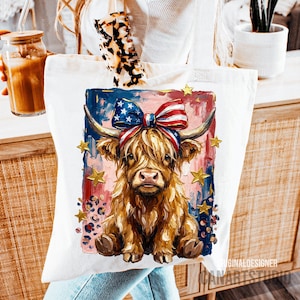 Peut inclure: Un sac fourre-tout blanc avec une illustration color&eacute;e d'une vache des Highlands portant un n&oelig;ud patriotique. La vache a de longs poils bruns et hirsutes, sur un fond de coups de pinceau bleus, rouges et roses avec des &eacute;toiles dor&eacute;es.