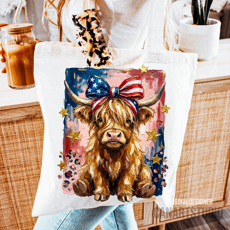Peut inclure: Un sac fourre-tout blanc avec une illustration color&eacute;e d'une vache des Highlands portant un n&oelig;ud patriotique. La vache a de longs poils bruns et hirsutes, sur un fond de coups de pinceau bleus, rouges et roses avec des &eacute;toiles dor&eacute;es.