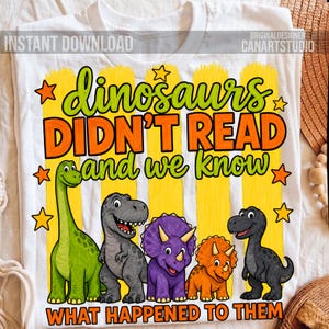 May include: A white t-shirt featuring a graphic with the text "dinosaurs DIDN'T READ and we know WHAT HAPPENED TO THEM". The design includes five colorful cartoon dinosaurs in green, gray, purple, and orange, set against yellow vertical stripes.