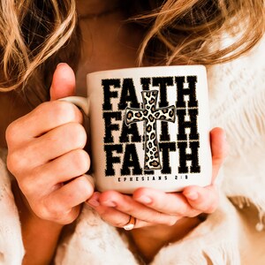 May include: White ceramic mug with a black and white graphic of the word "FAITH" repeated three times with a leopard print cross in the center. The text "EPHESIANS 2:8" is printed below the graphic.
