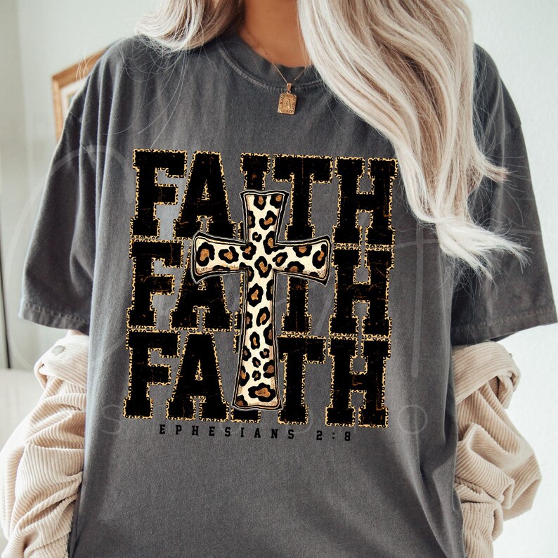 May include: A gray t-shirt with the word "FAITH" repeated three times in black with a leopard print cross in the center. The text "EPHESIANS 2:8" is printed below the word "FAITH".