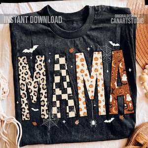 May include: Dark grey t-shirt featuring the word "MAMA" in various patterns. The letters are decorated with leopard print, a black and white checkerboard, pumpkins, and Halloween designs. Bats, spiderwebs, and leaves are also featured.
