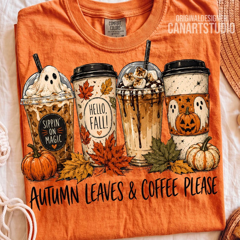 May include: An orange t-shirt featuring a graphic of four coffee cups decorated with ghosts, pumpkins, and autumn leaves. The text reads "Sippin' on magic", "Hello, fall!", and "Autumn leaves & coffee please". The shirt has a Comfort Colors label.