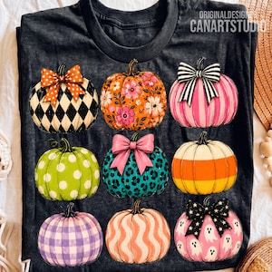 May include: A dark grey t-shirt featuring nine pumpkins with various patterns including black and white diamonds, floral orange, pink stripes, green polka dots, leopard print, candy corn colours, purple plaid, wavy orange, and ghost prints with bows.