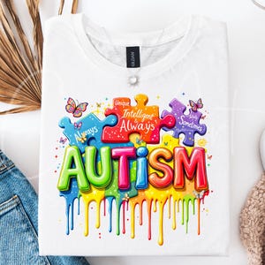 May include: White t-shirt with a colorful graphic design of puzzle pieces spelling out "AUTISM". The puzzle pieces have text on them that reads "Unique", "Intelligent & Always", "Really Sometimes Mysterious".