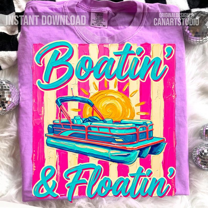 May include: A light purple t-shirt with a graphic design featuring a pontoon boat, sun, and the words "Boatin' & Floatin'" in turquoise. The design has a retro, textured look with pink and yellow stripes.
