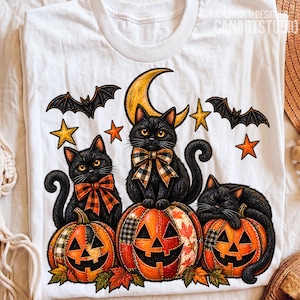 Può includere: Una t-shirt bianca con un'illustrazione grafica di tre gatti neri dagli occhi gialli con fiocchi a quadri, seduti su tre zucche intagliate. Il design include una mezzaluna gialla, stelle e pipistrelli, con il testo ORIGINALDESIGN CANARTSTUDIO.