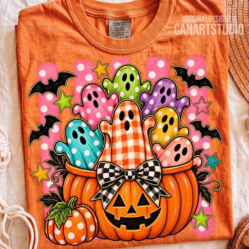 May include: An orange t-shirt featuring a graphic of a large jack-o'-lantern filled with colorful ghosts in polka dot and gingham patterns. The design includes black bats, yellow and green stars, and a black and white checkered bow on the pumpkin.